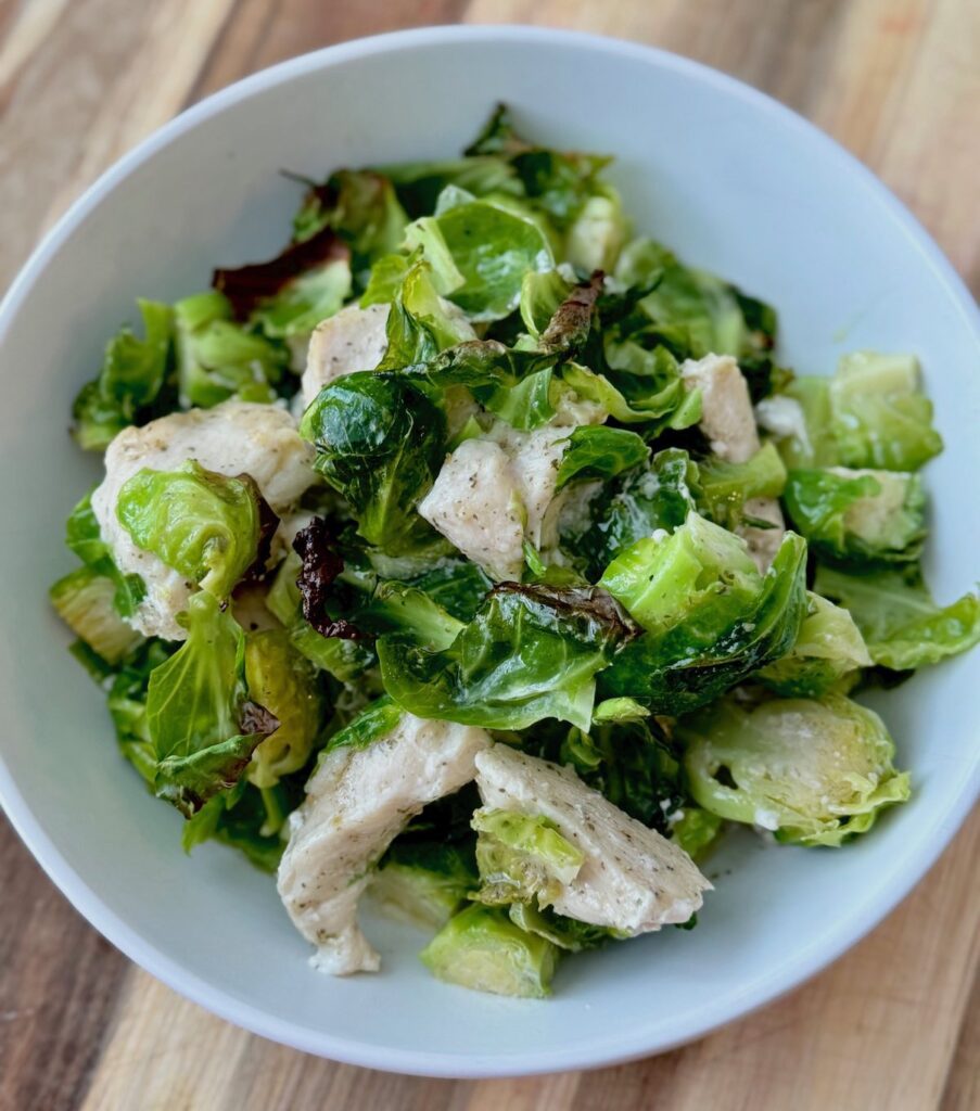 chicken with ranch seasoning and colorful roasted brussel sprouts, in a white bowl