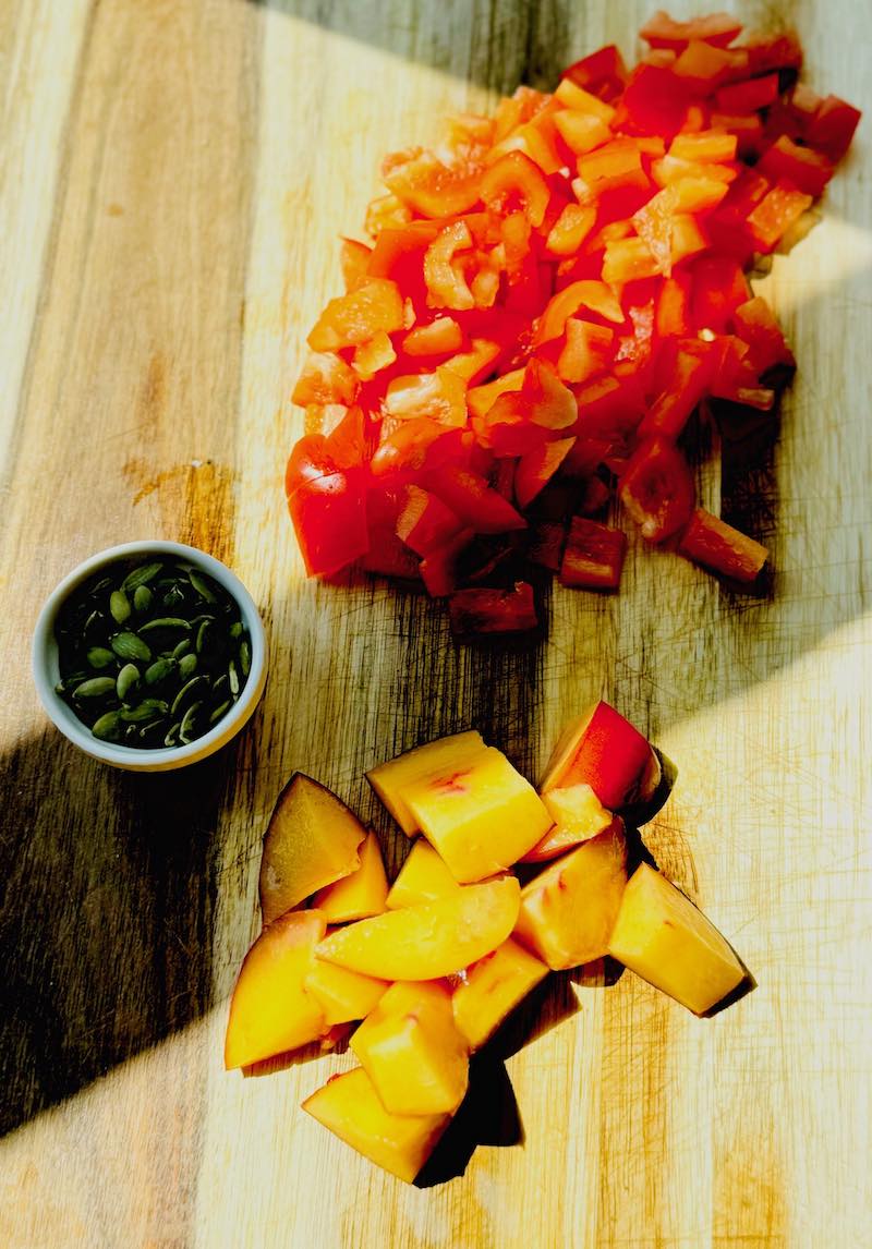 fresh pepitas, diced raw peppers and nectarine on board