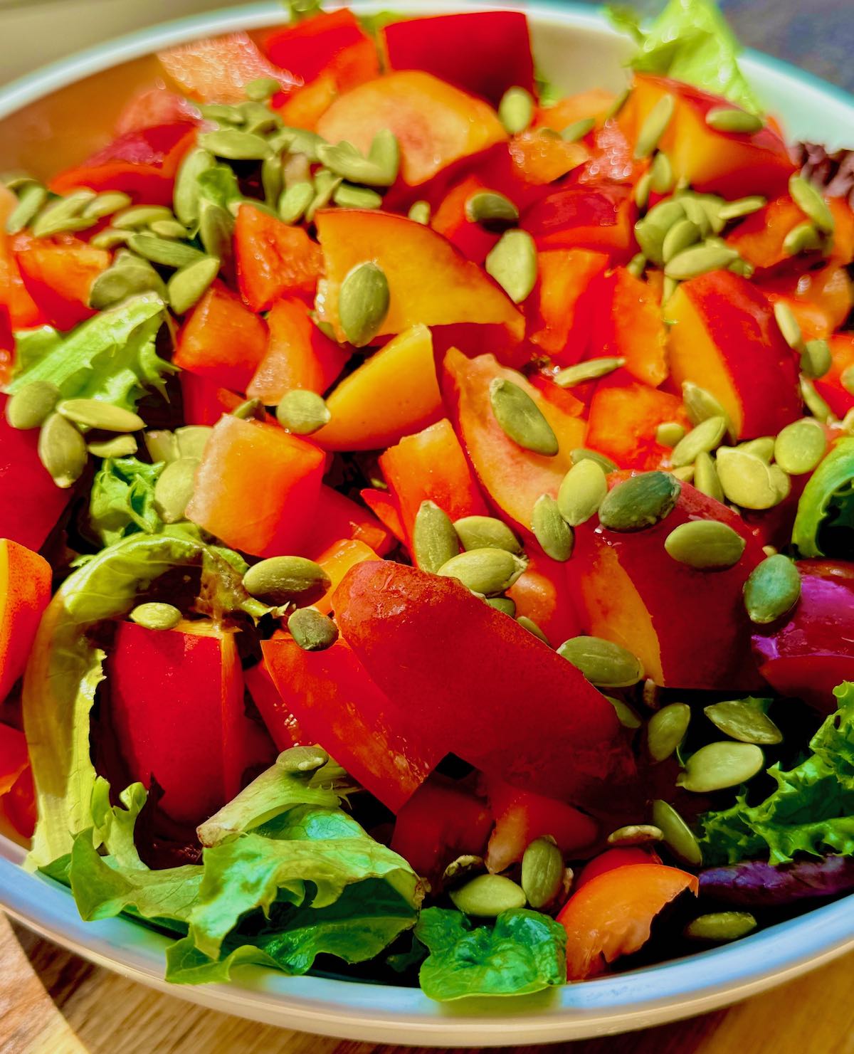 raw vegan salad recipe topped with pepitas in bowl
